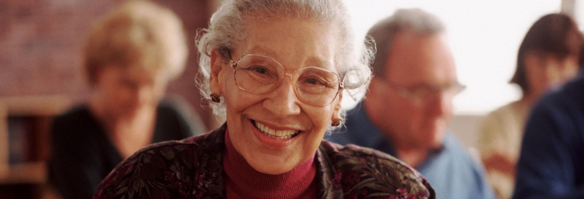 Elderly adult female smiling in classroom.