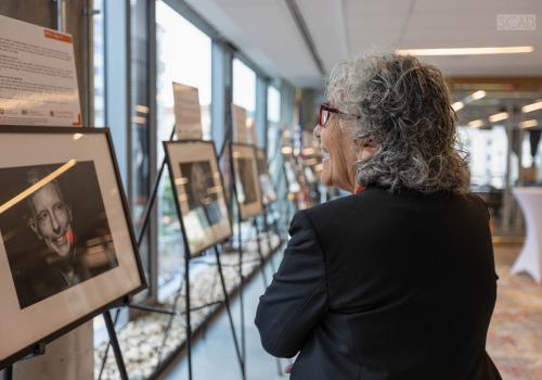 Mindy Fain, MD, admires a row of photos of happy smiling older adults in the Aging With Edge photography exhibit.